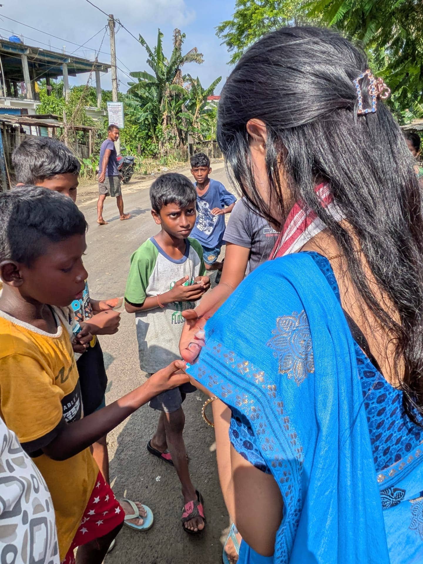 Bhairavi Aradhya Deka handing out supplies to children on a village road in Assam