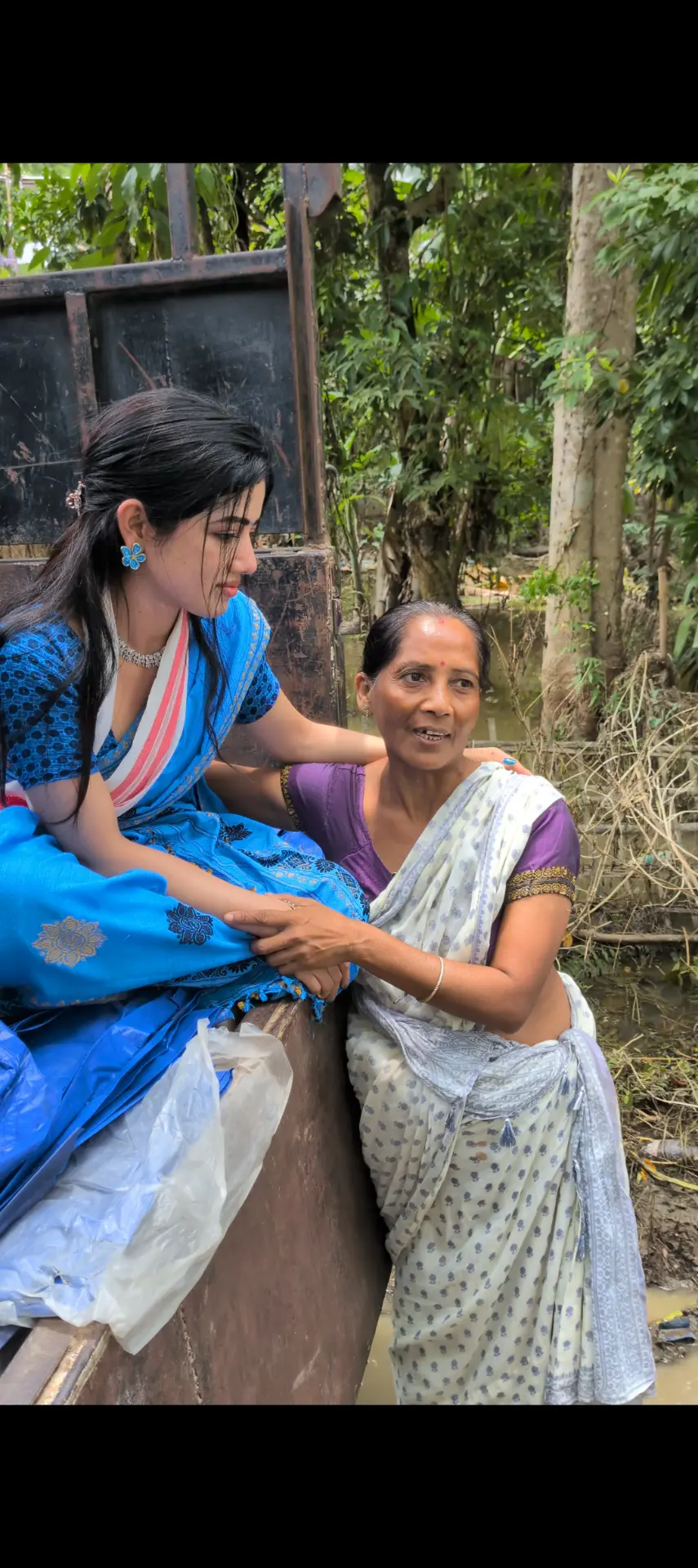 Bhairavi Aradhya Deka holding the hands of an elderly woman beside a relief boat